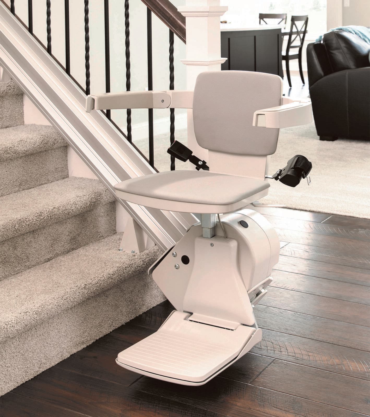 A modern straight stairlift installed on a carpeted staircase in a bright home
