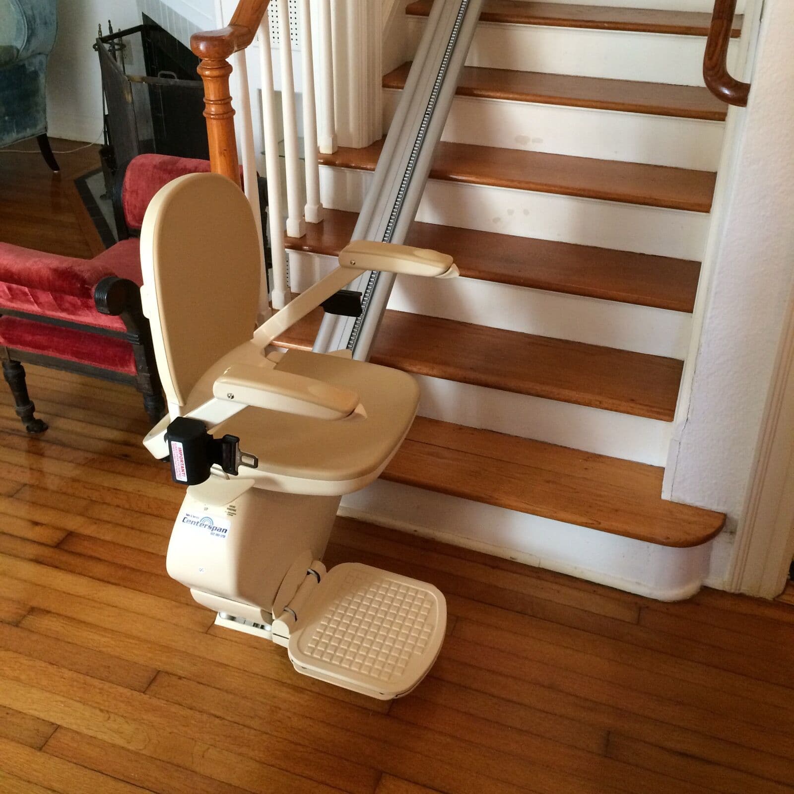 A straight stairlift parked at the bottom of a wooden staircase in a family home